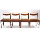 A set of four 1970’s teak rail-back dining chairs with padded seats; & on round tapered legs with