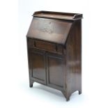 A mid-20th century small oak bureau with fitted interior enclosed by fall-front above a long