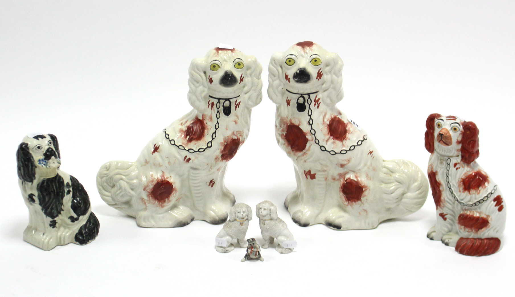 A pair of Staffordshire pottery flat-back seated spaniel ornaments, 12½” high; together with four