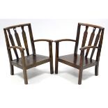 A pair of Scottish arts & crafts-style low elbow chairs, with carved splat backs, hard seats, & on