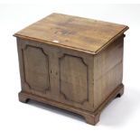 A mahogany small dwarf cabinet, enclosed by hinged lift-lid, with panelled front, & on shaped plinth