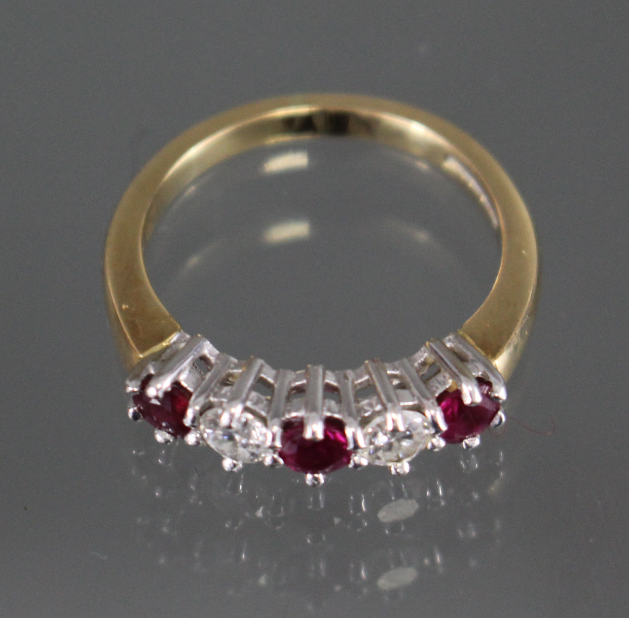 An 18ct. gold ring set three rubies with two diamonds in between; size: K/L; weight: 4.2gm.