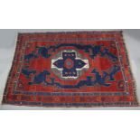 A Persian rug of crimson, blue, & ivory ground, with central medallion in herringbone & floral