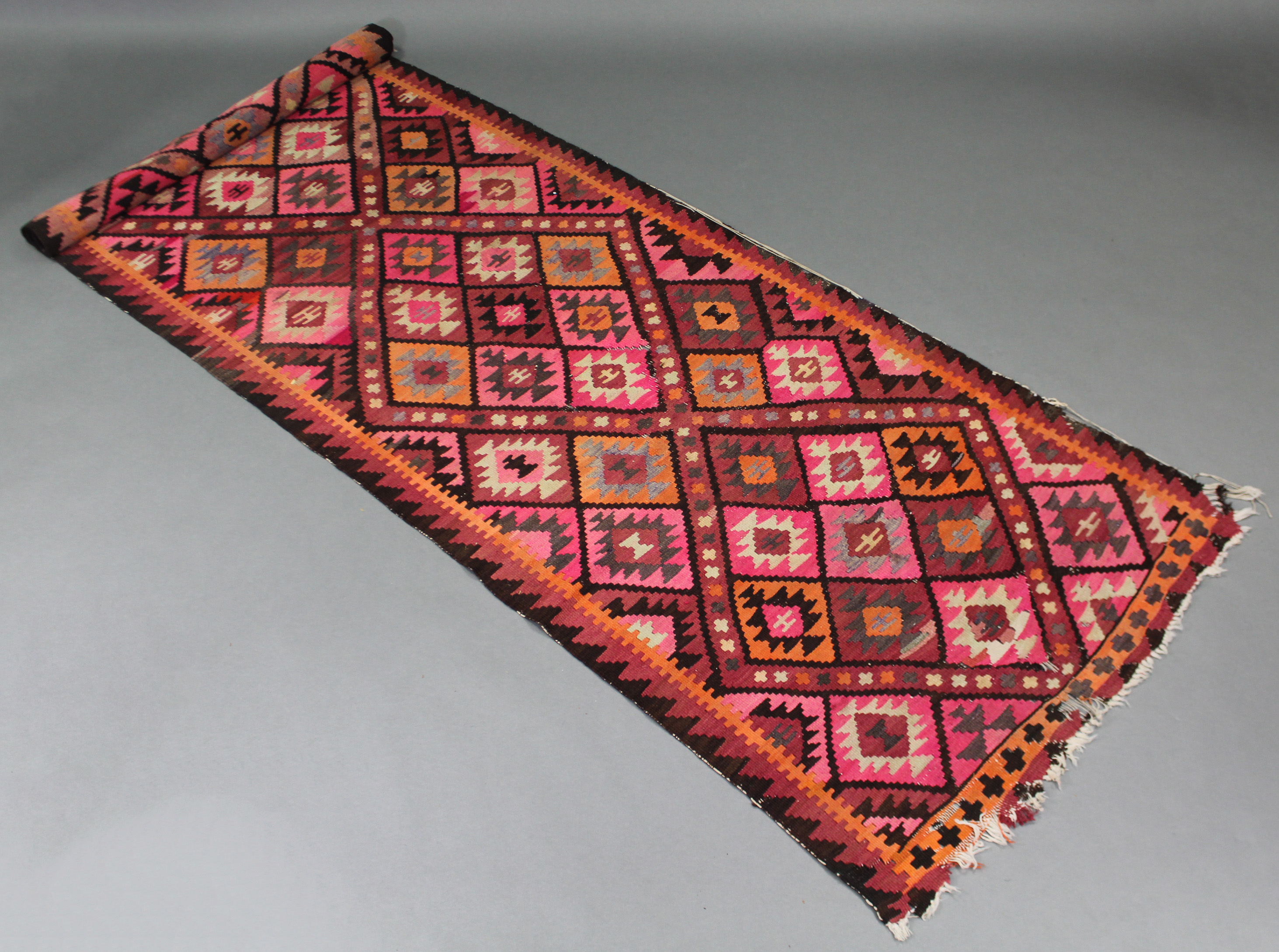 A Kelim runner of pink ground, with all-over geometric lozenge design; 11’ x 3’ 4” (worn).