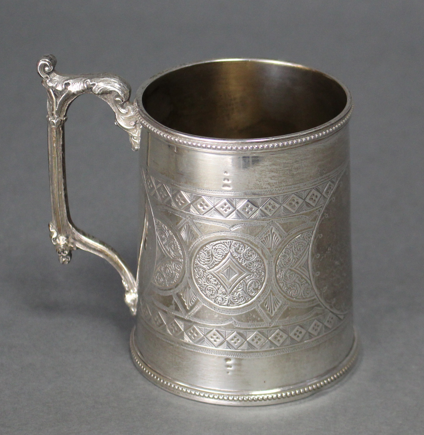 A Victorian silver round tapered mug with cast gothic leaf-scroll handle, beaded rims, & engraved - Image 2 of 3