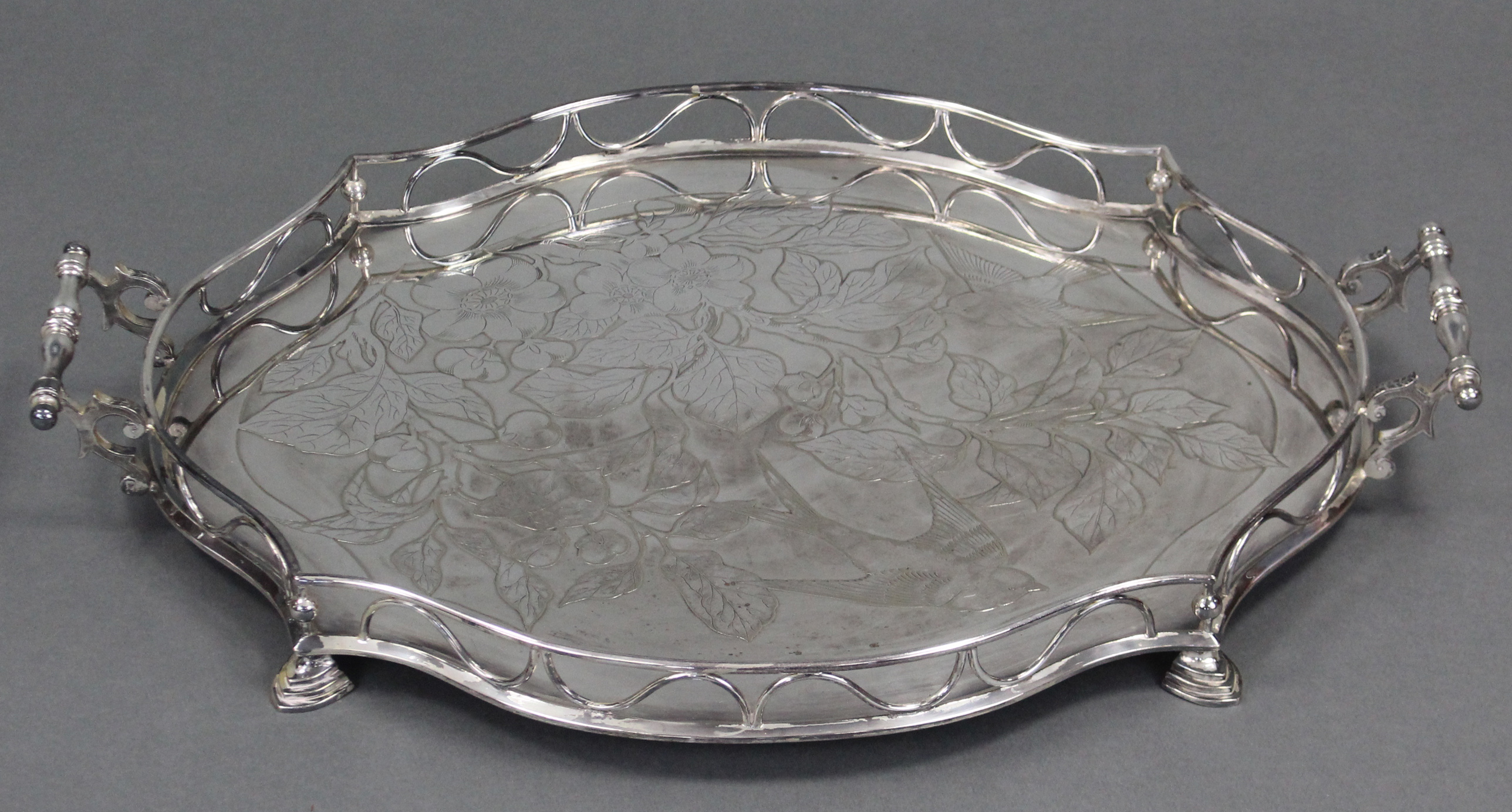 An Edwardian silver-plated shaped oval two-handled tray with embossed decoration of a bird amongst