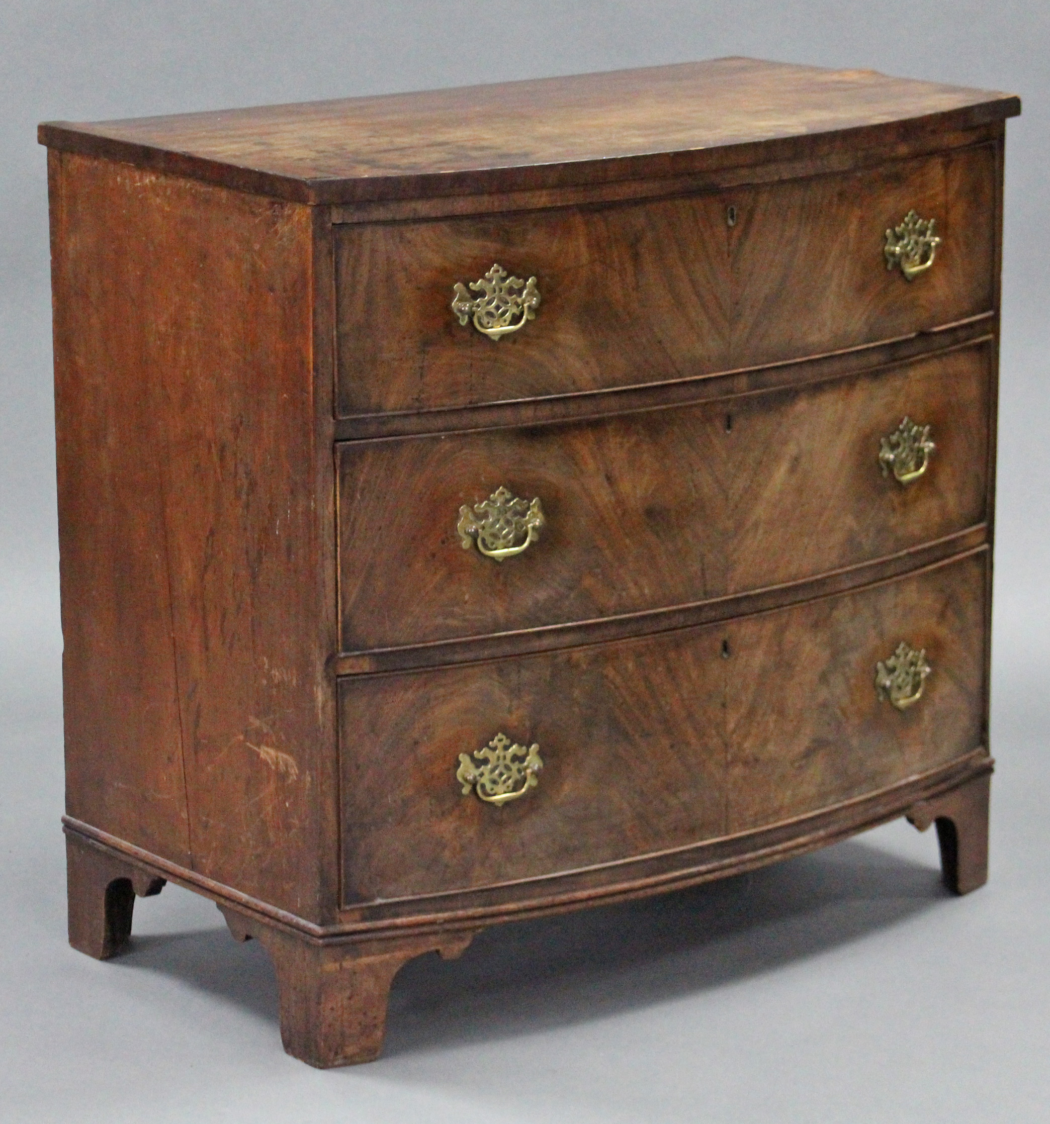 An early 19th century figured mahogany bow-front chest fitted three long graduated drawers with