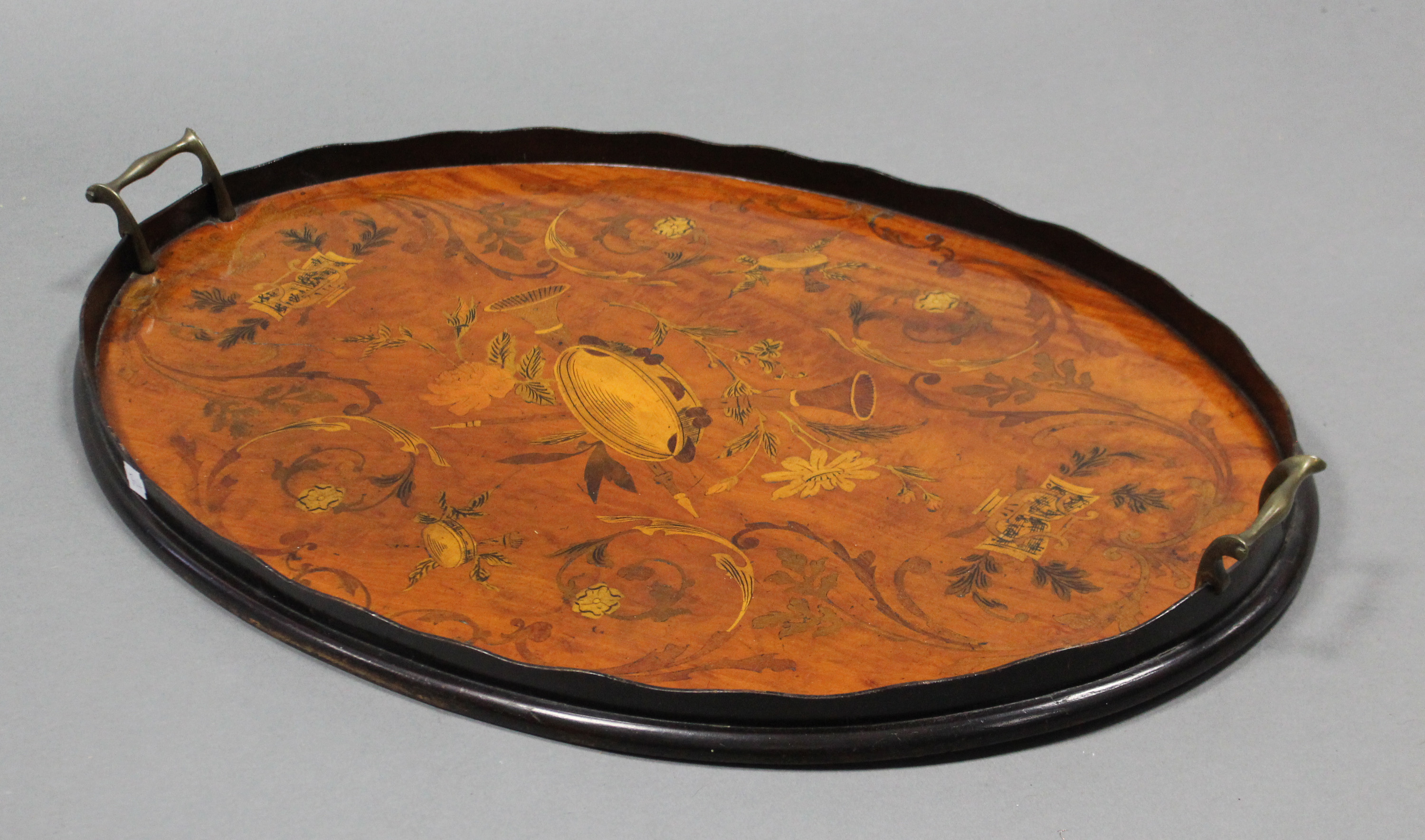 A 19th century mahogany oval tray with marquetry decoration of musical instruments & floral scrolls,