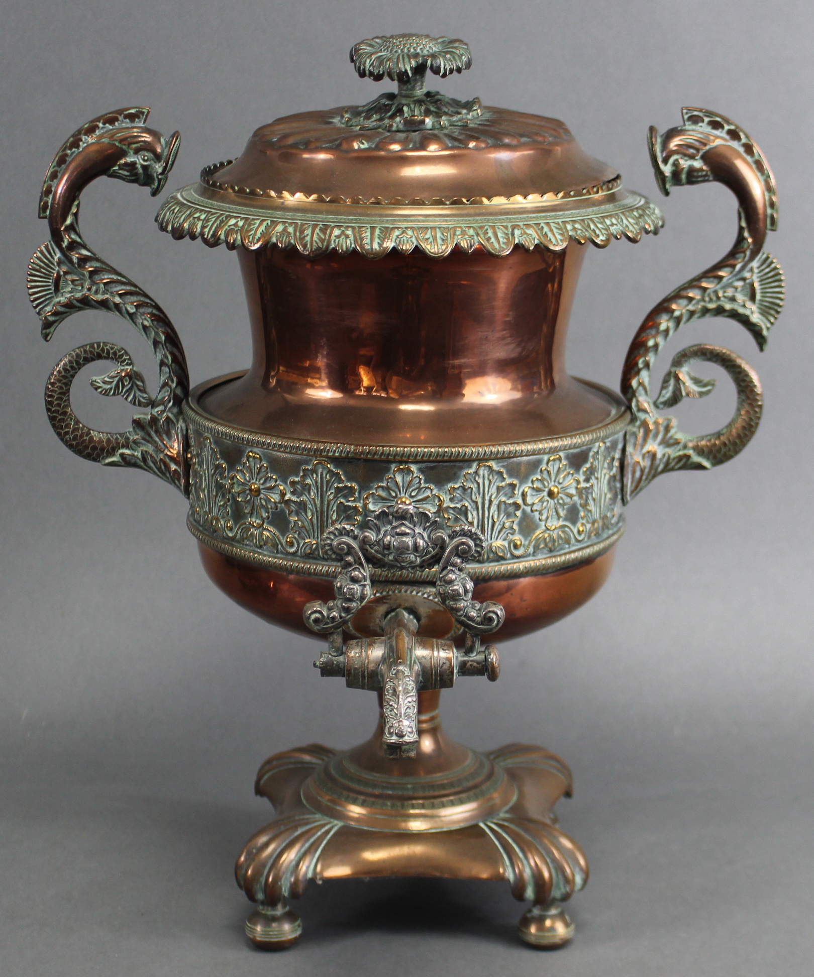 An early 19th century copper samovar with embossed foliate decoration, dolphin side handles, &