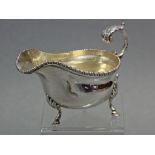An Edwardian silver oval sauce boat with gadrooned rim, open acanthus scroll handle, & on three