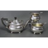 A George V silver three-piece tea service in the regency style, of compressed oblong form with