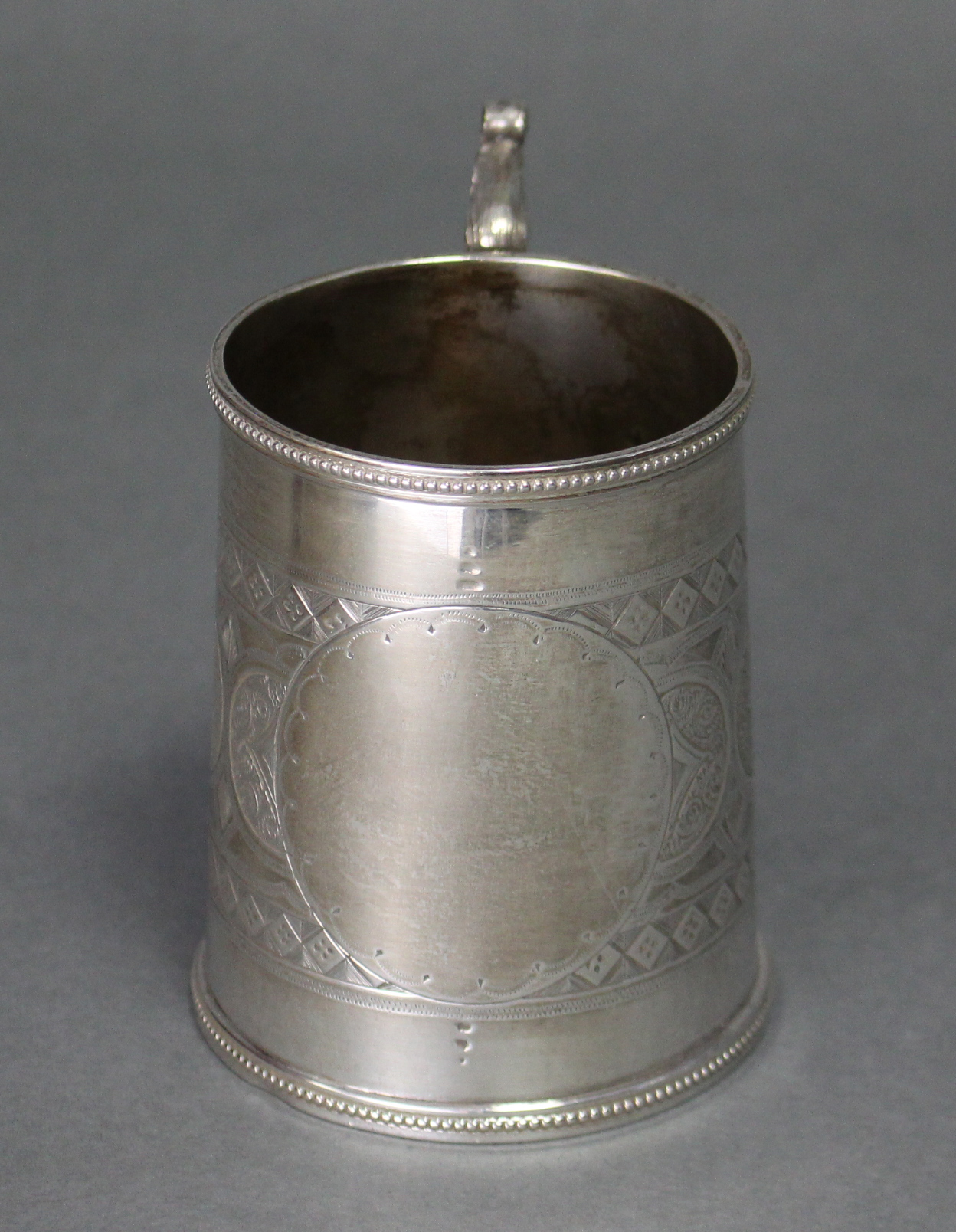 A Victorian silver round tapered mug with cast gothic leaf-scroll handle, beaded rims, & engraved - Image 3 of 3