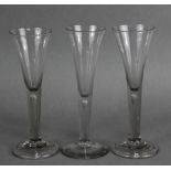 Three 18th century tall drinking glasses, each with narrow trumpet bowl & tear drop stem, two with