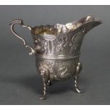 An Irish Victorian silver helmet-shaped cream jug with chased decoration of animals, birds, &