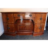 A SHERATON FIGURED MAHOGANY BOW-FRONT SIDEBOARD, fitted with a central frieze drawer above a