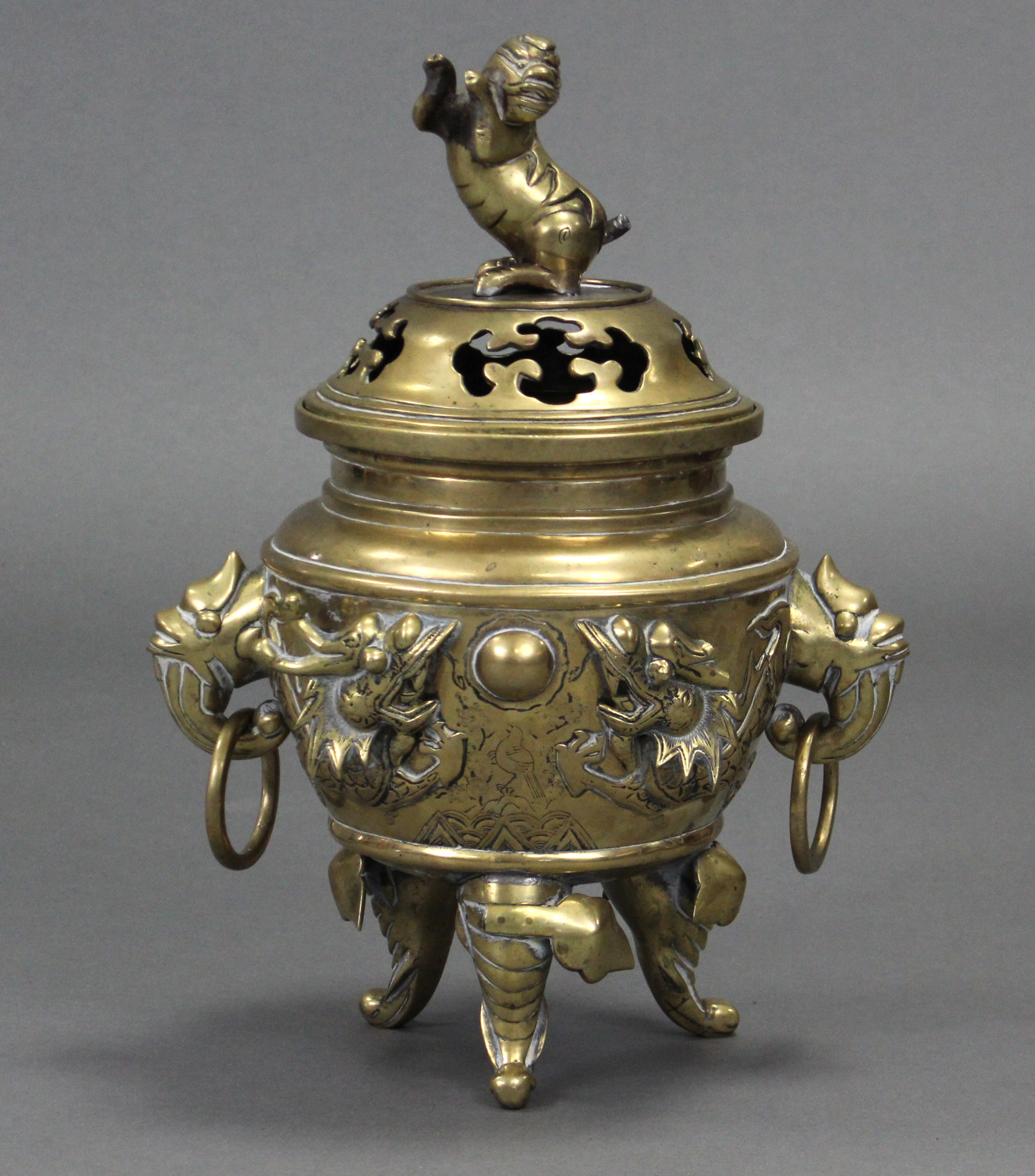 A Chinese cast brass tripod censer with raised decoration of dragons chasing the pearl & with