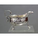 A George II silver small sauce boat with cut-card rim, open acanthus scroll handle, &on three pad