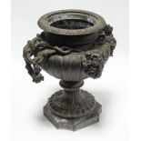 A 19th century bronze urn of fluted ovoid form, with grapevine side handles & Bacchus masks, on