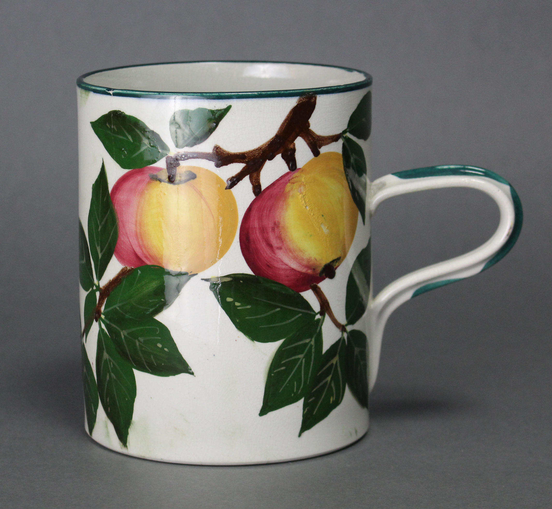 A Wemyss Ware (R. Heron & Son) pottery large cylindrical mug painted with the “Apples” pattern;