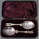 A pair of continental serving spoons with plain oval bowls, the ornate cast stems with figure