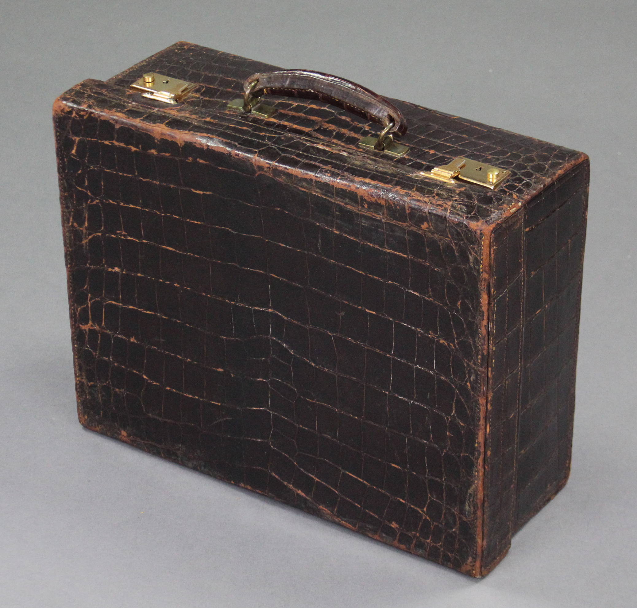 A brown crocodile skin suitcase with gilt-brass twin locks, retailed by Edwards & Sons, Regent