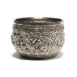 A Burmese white metal small bowl, the rounded sides embossed with elephants & other animals below