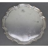 A George VI silver salver of circular shape with raised “pie-crust” border, & on four scroll feet,
