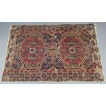 A Persian rug of crimson, deep blue, & ivory ground, with pair of central lozenges & all-over