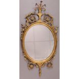 An Adam-style gilt-frame oval wall mirror with vase surmount, foliate scroll border & husk-swag