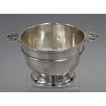A George V silver deep circular bowl, the flat side handles pierced with initials “B. H. B”, on