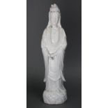 A Chinese blanc-de-chine porcelain standing figure of Guanyin, wearing flowing robes, on rocky base;