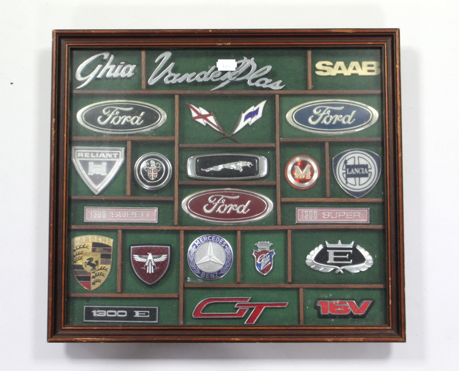 A framed display of various car emblems & badges including Porsche, Jaguar, Lancia, etc. together