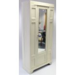 A late Victorian cream painted wardrobe, enclosed by rectangular bevelled mirror door to centre & on