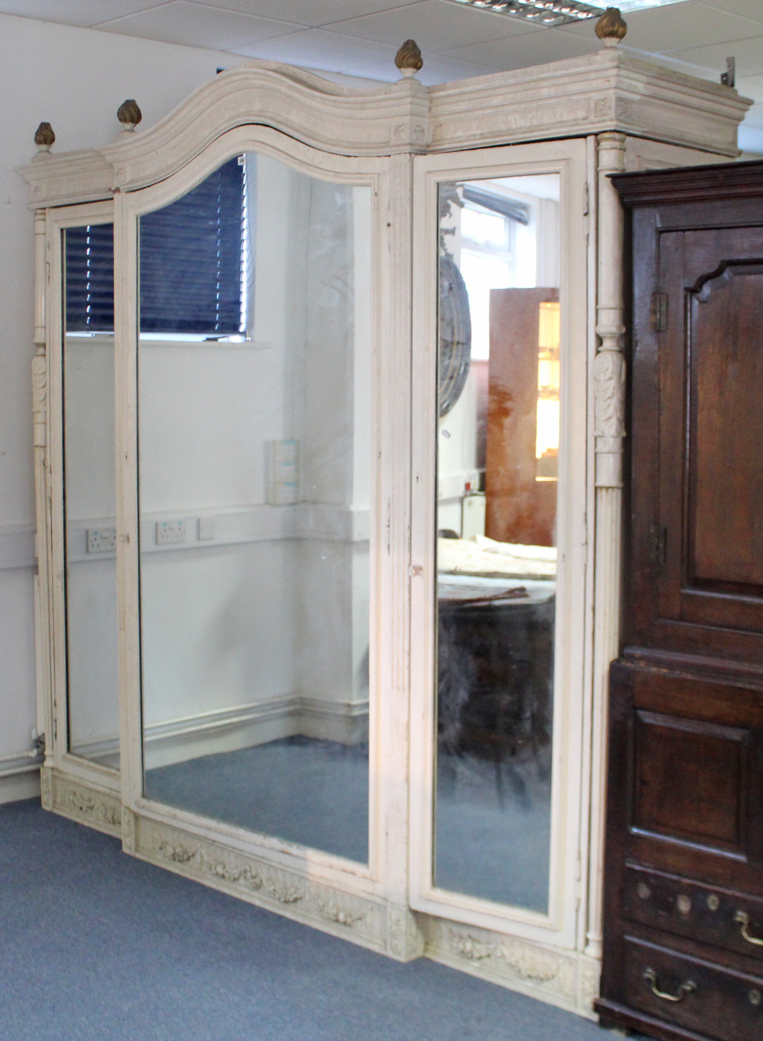 A large painted mahogany wardrobe with shaped cornice, panel door to centre with mirror door