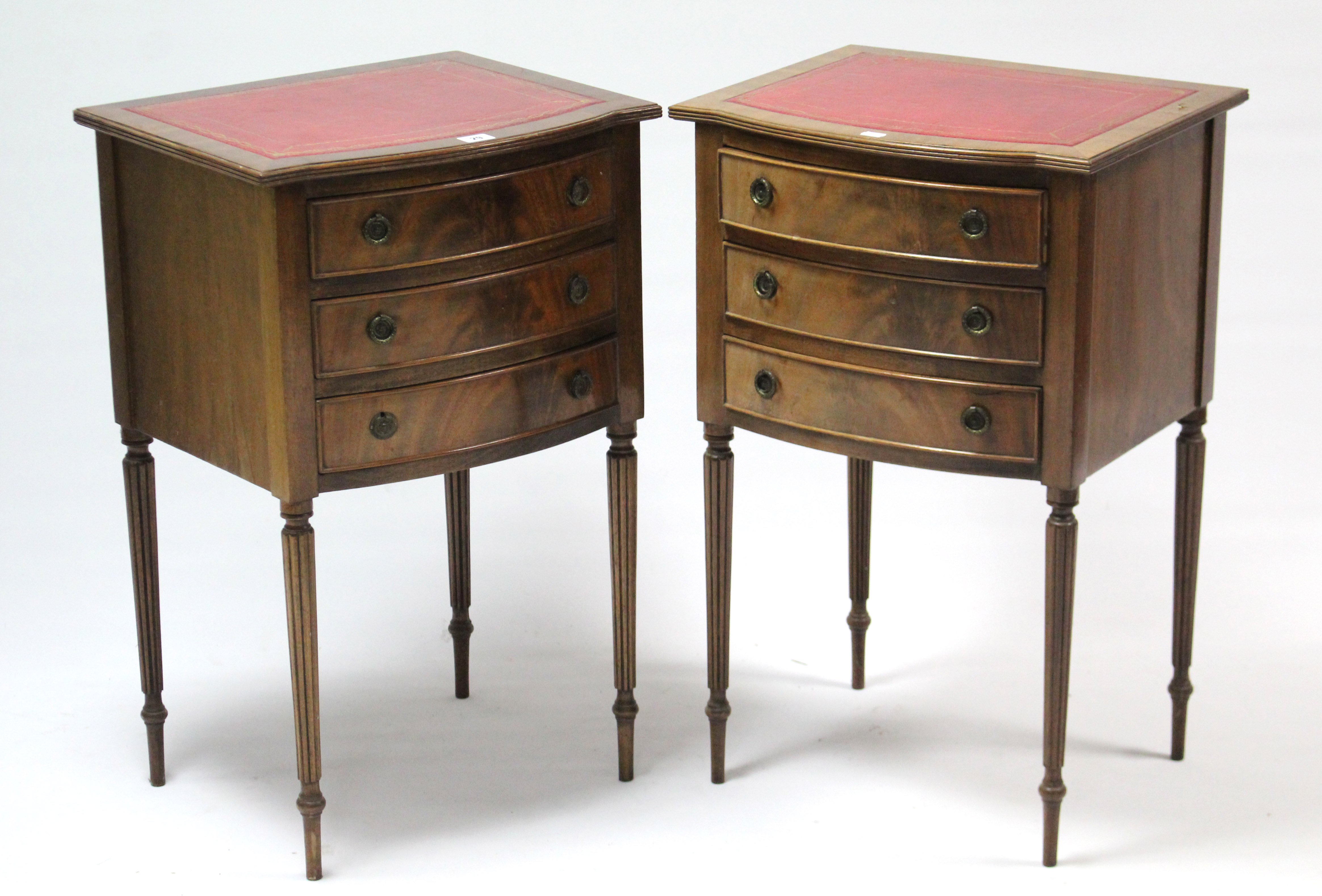 A pair of mahogany bow-front bedside chests each inset gilt-tooled crimson leather, fitted three