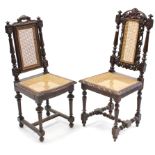 A pair of Carolean-style carved oak hall chairs each with woven can seat & back, & on turned &