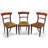 A set of three William IV mahogany bow-back dining chairs with padded drop-in seats, & on turned &