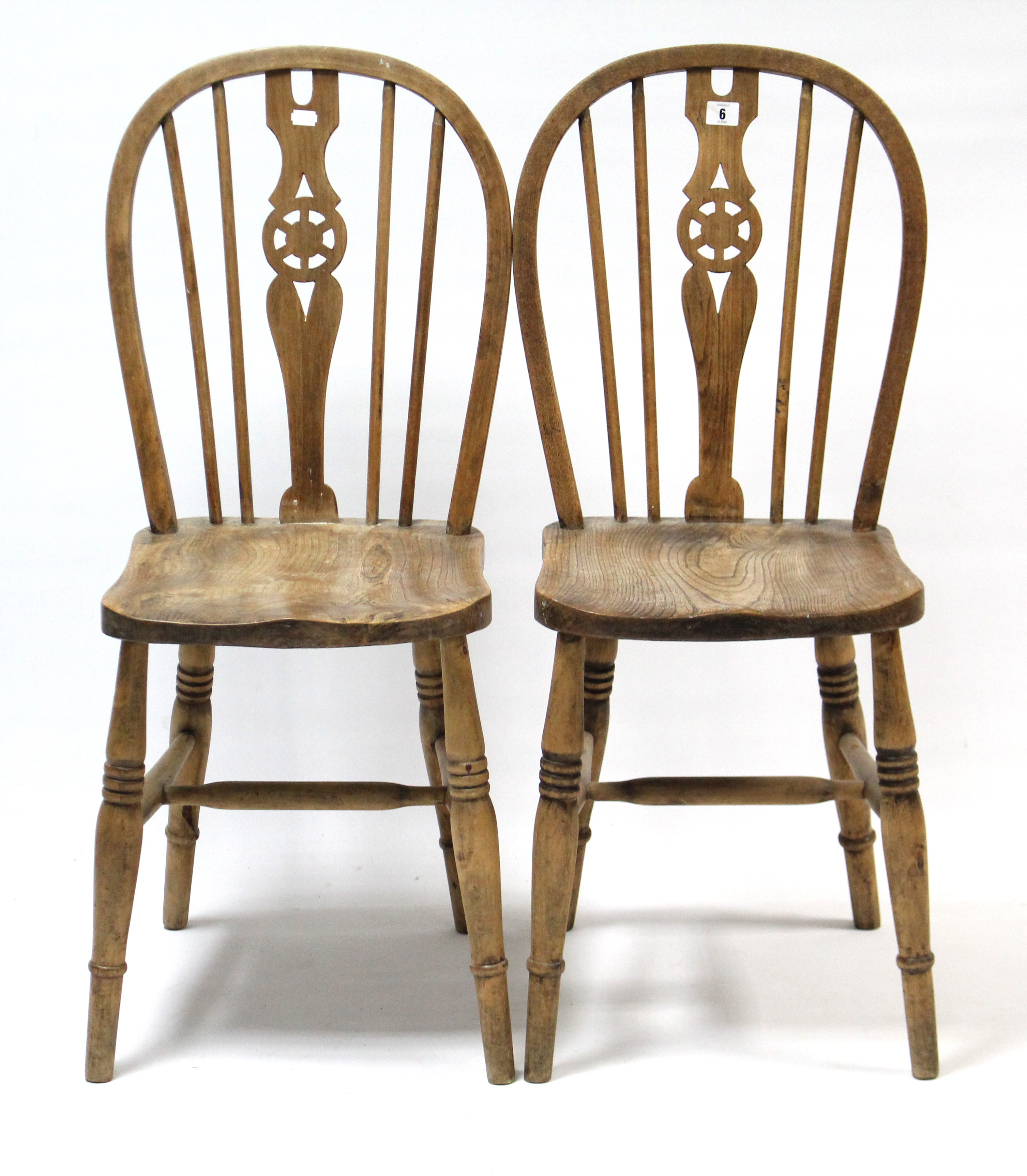 A pair of Windsor-style wheel-back kitchen chairs with hard seats, & on ring-turned legs with