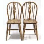 A pair of Windsor-style wheel-back kitchen chairs with hard seats, & on ring-turned legs with