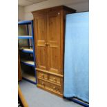 A pine wardrobe enclosed by pair of panel doors above two short & one long drawer, & on plinth base,
