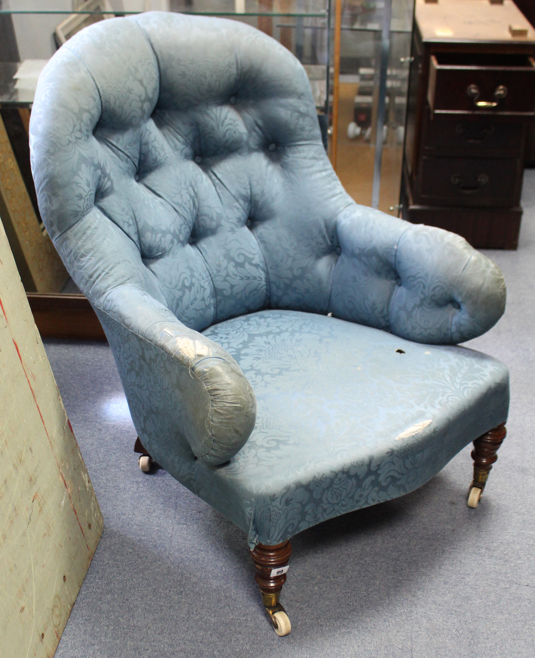 A late Victorian buttoned-back armchair (requires reupholstering), on short ring-turned legs with