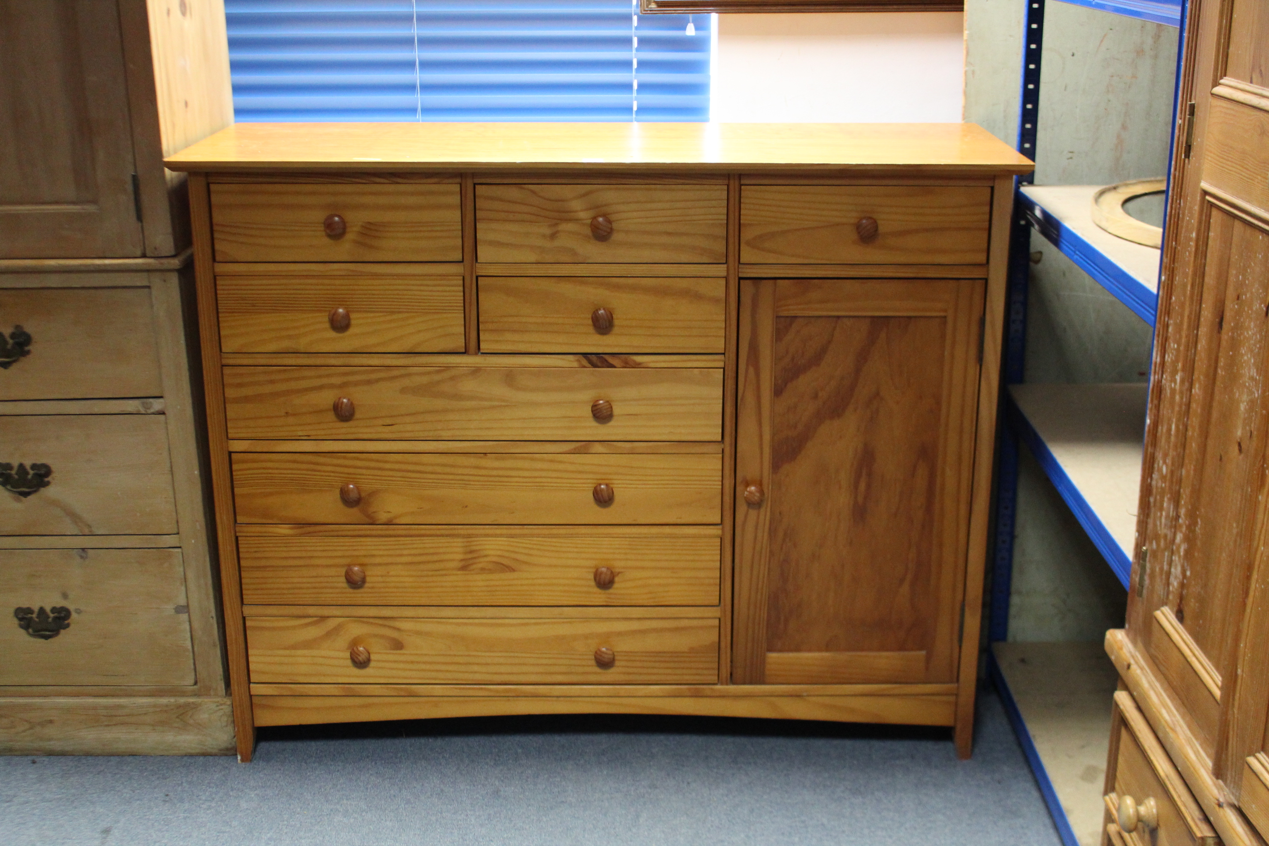 A modern pine combination chest/cupboard, fitted with an arrangement of nine drawers & enclosed by a