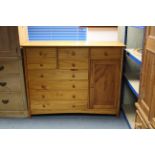 A modern pine combination chest/cupboard, fitted with an arrangement of nine drawers & enclosed by a