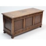 A 20th century oak coffer with hinged lift-lid, blind fret-work frieze, panelled sides, & on