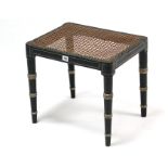 A regency-style ebonised painted cane-seat dressing table stool on ring- turned tapered legs, 18”