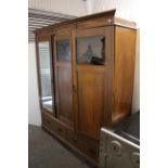 A late 19th/early 20th century oak triple-door wardrobe, with fitted interior enclosed by