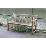 A teak slatted garden bench on square legs, 57¾” long.
