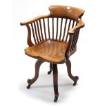 An early 20th century hardwood lath-back swivel desk chair, on four slender cabriole legs with