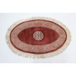 A pair of Chinese oval rugs of pink & coral ground, 50” x 31”.