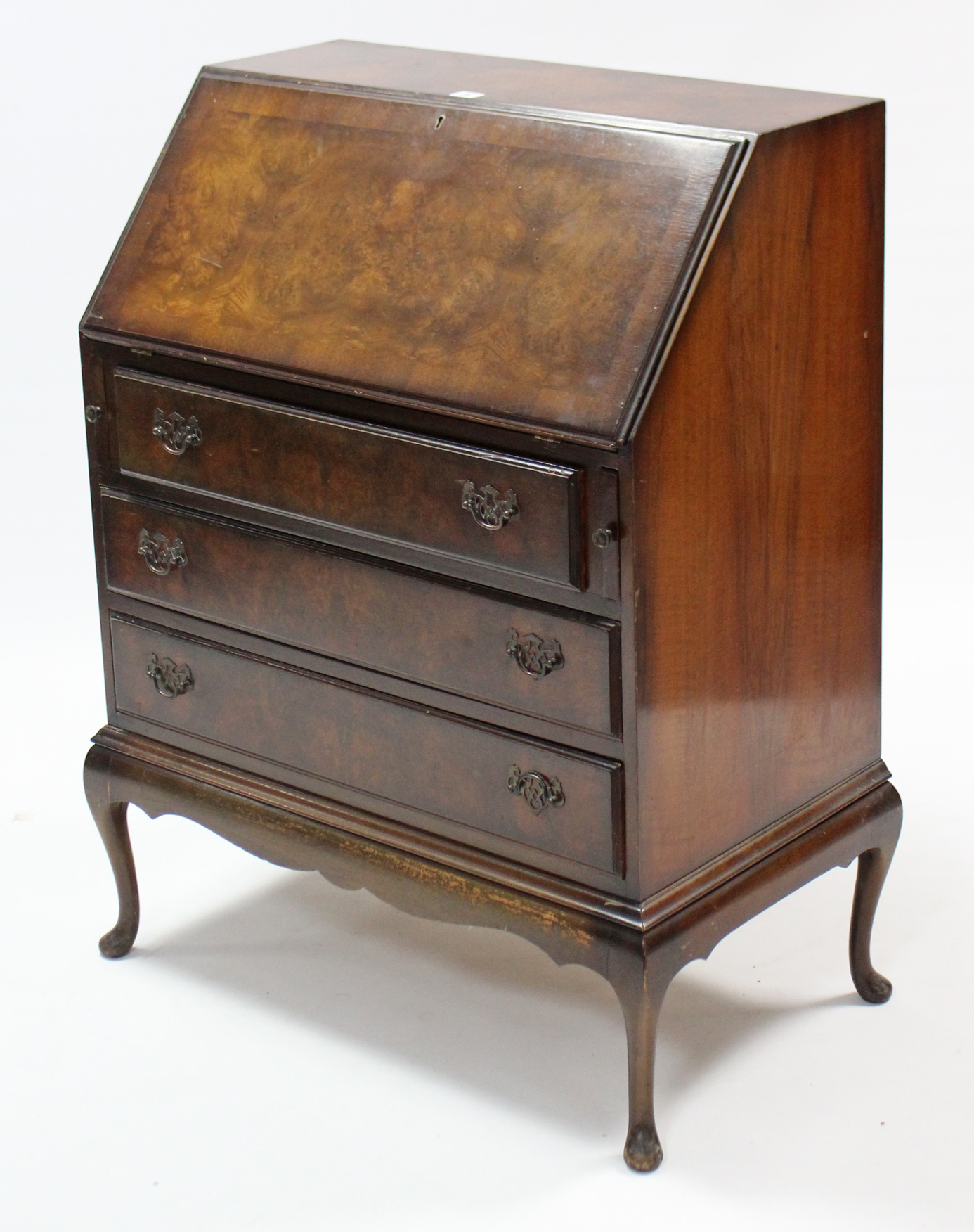 A walnut bureau with fitted interior enclosed by fall-front above three long graduated drawers, & on